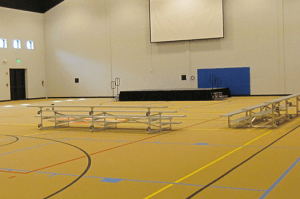 Empty Messiah gymnasium with empty bleacher seats in front of blank projector screen